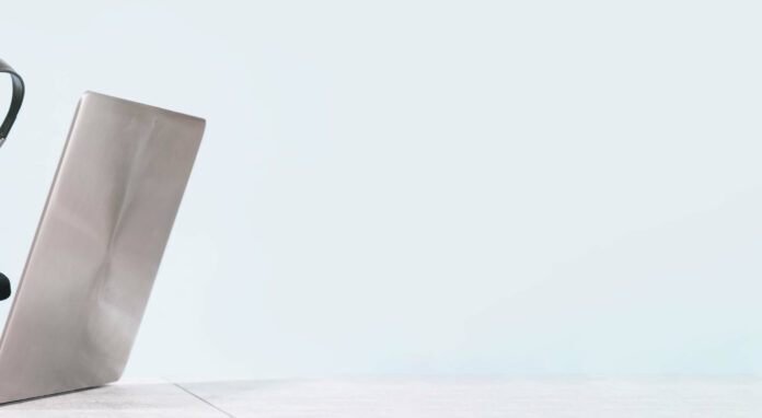 Online DSH training: A person sits in front of a laptop and holds a headset in their hand.