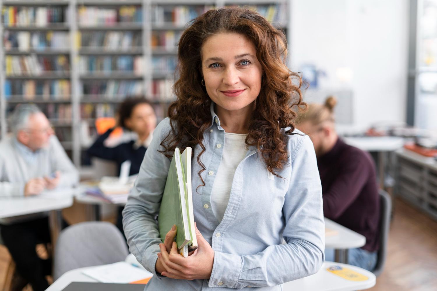 Integration courses for participants with little formal learning experience: A woman stands in front of a german course with international participants and smiles.