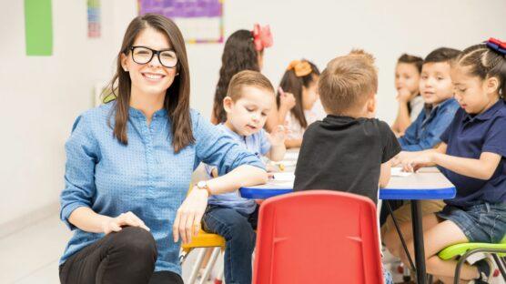 Berufssprachkurs Deutsch für Frühpädagogik: Eine Erzieherin steht vor einer Gruppe kleiner Kinder in einer Kita.